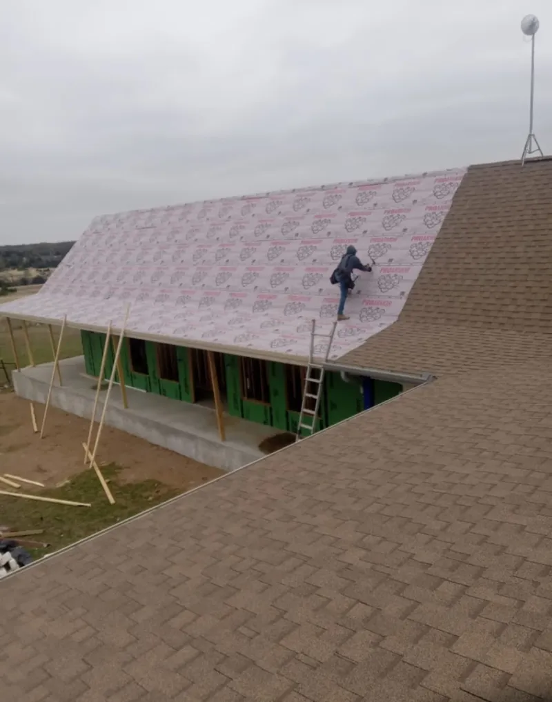 Worker preparing underlayment for a metal roof installation in Crystal